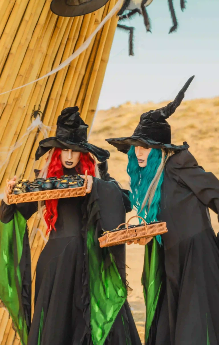 Costumed performers dressed as witches welcoming guests at a Halloween desert event.