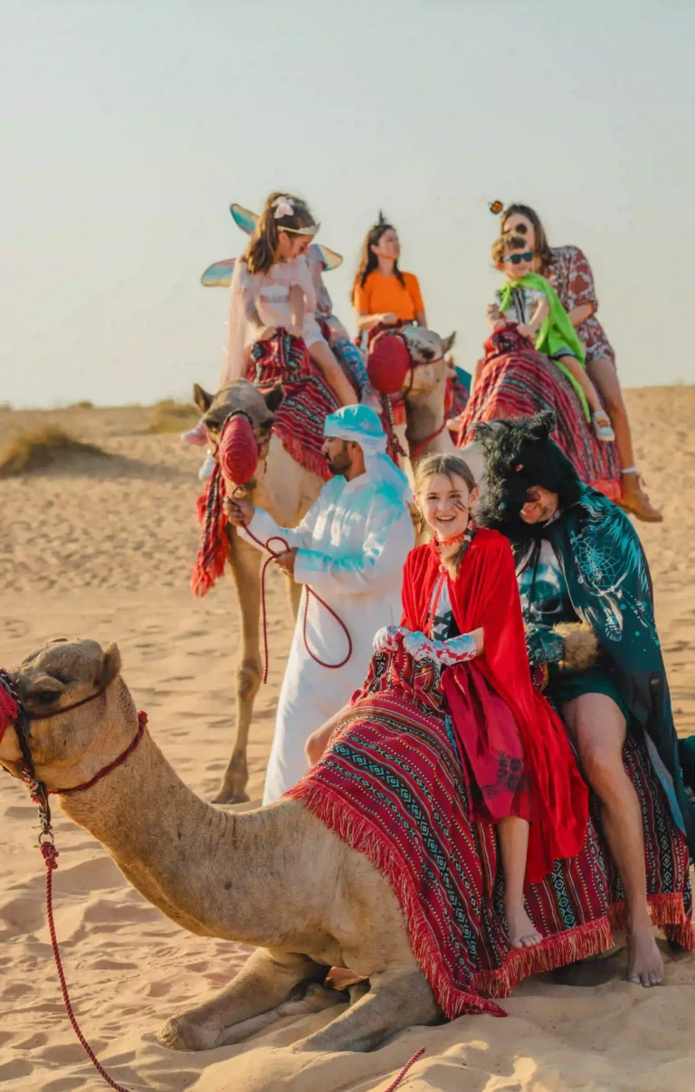 amilies in Halloween costumes enjoying a camel ride as part of a festive desert celebration.