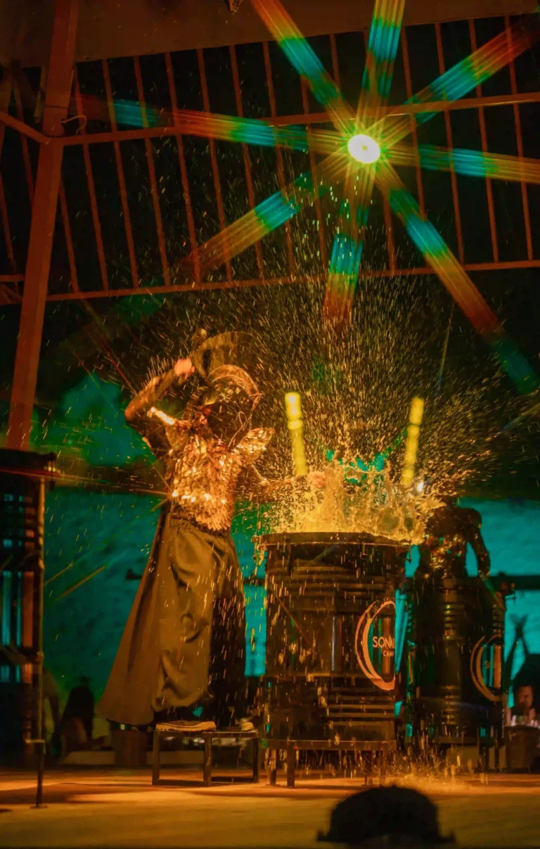 Water warrior drum performance featuring dramatic lighting and special effects at an immersive evening event.