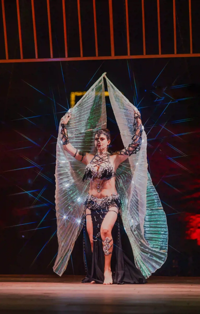 Belly dancer performing on stage under theatrical lighting during a Halloween celebration.