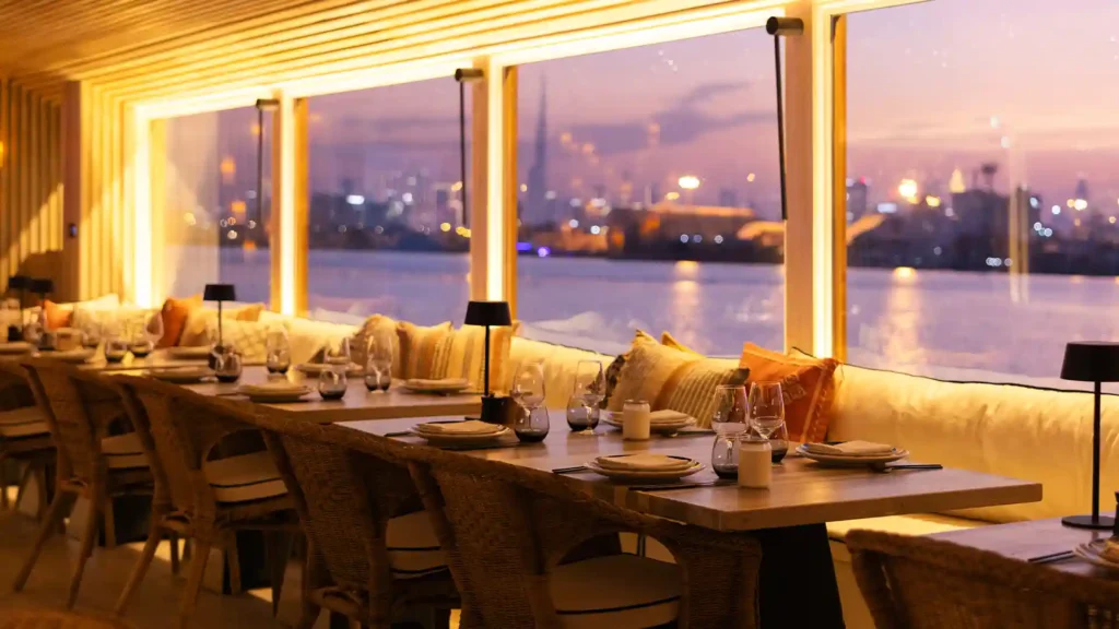 Lady Nara dhow illuminated at night on the Arabian Gulf with Dubai skyline in the background
