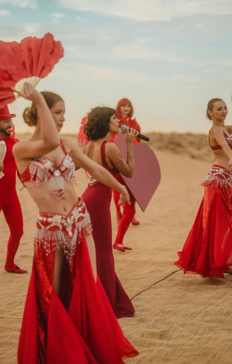 Valentine’s Day dance performance featuring red costumes and handheld fans in the desert.